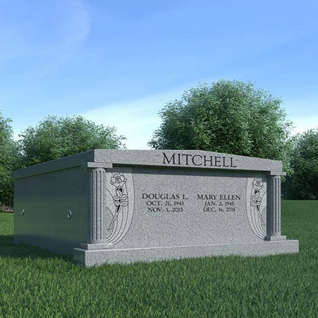 Grave monument with 'Mitchell' family name and inscriptions in a park-like setting.